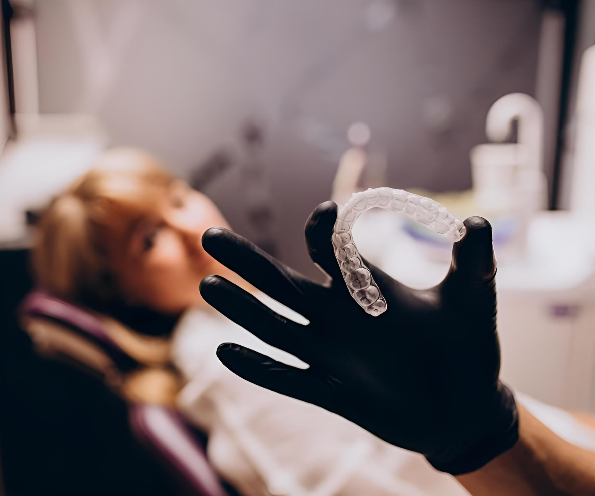 a hand holding a clear plastic retainer