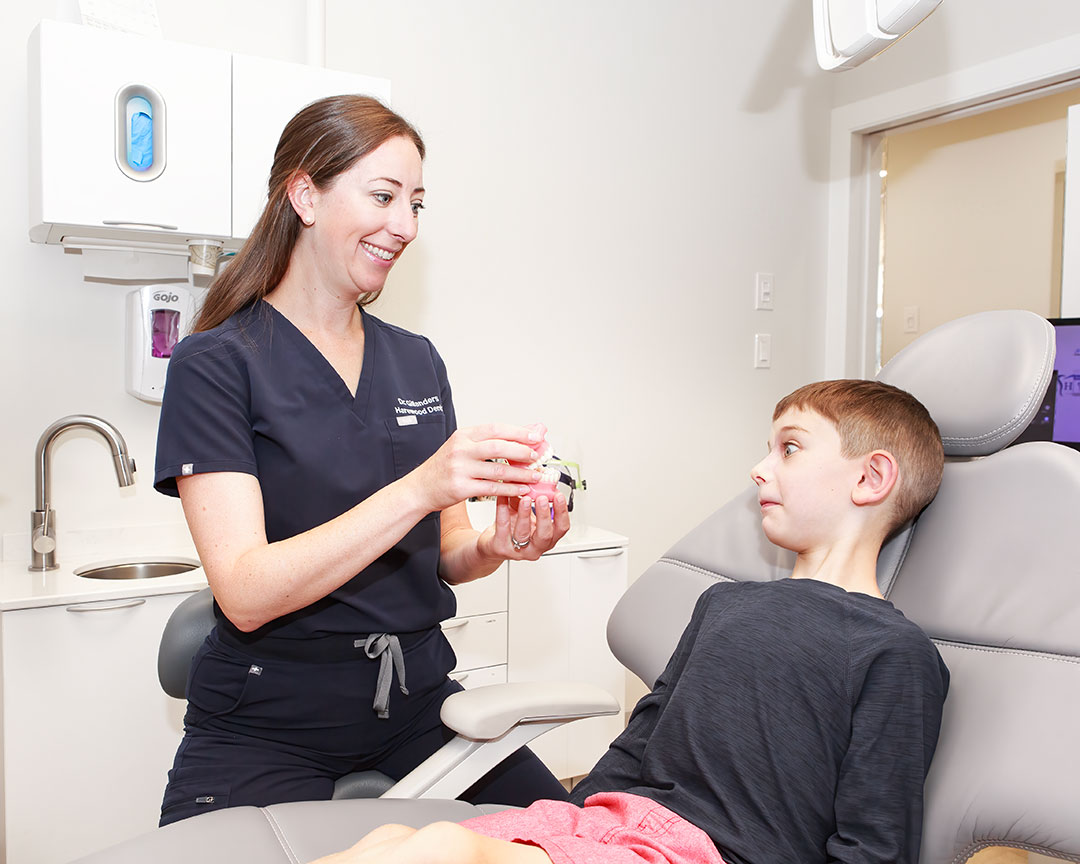 a woman holding a small object to a boy in a chair