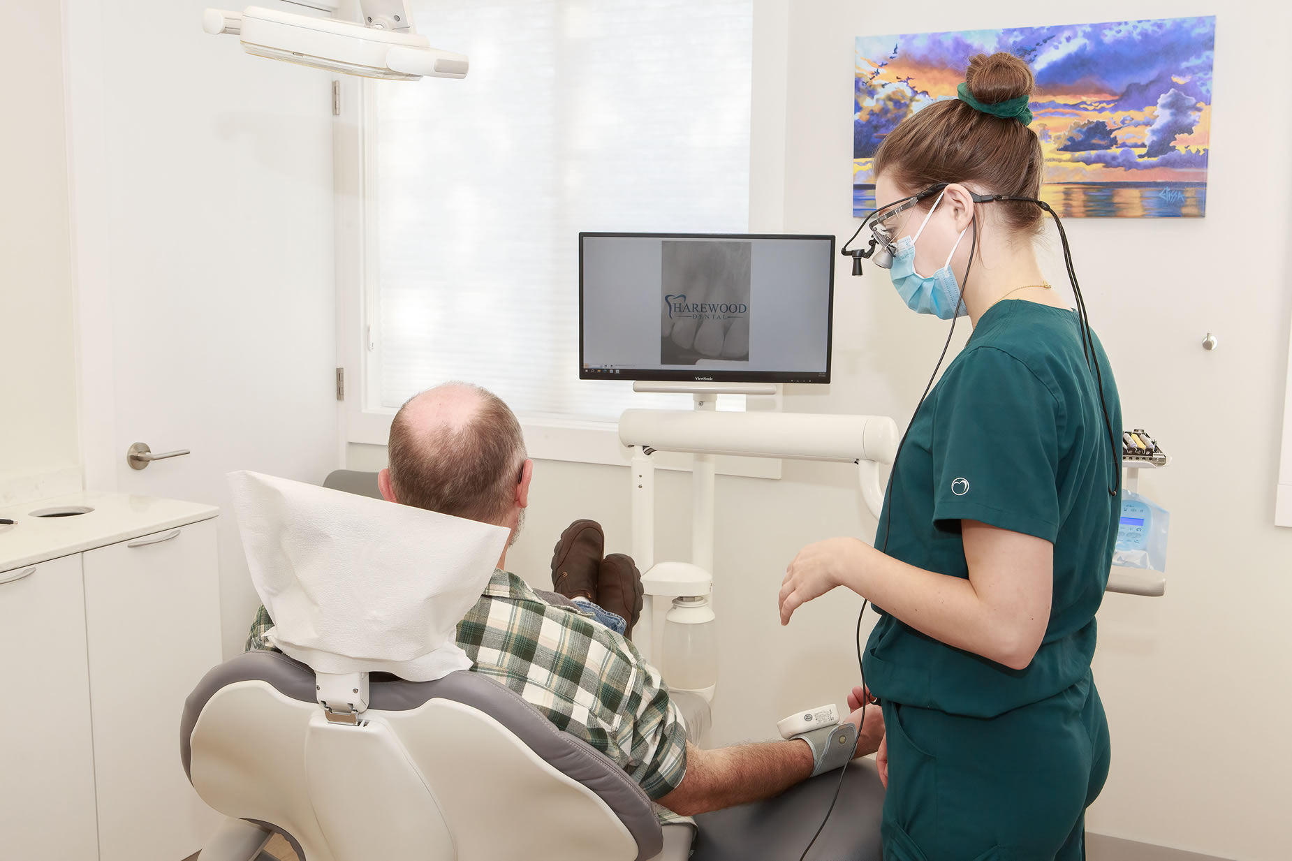 a woman in a mask and green scrubs sitting in a chair next to a man