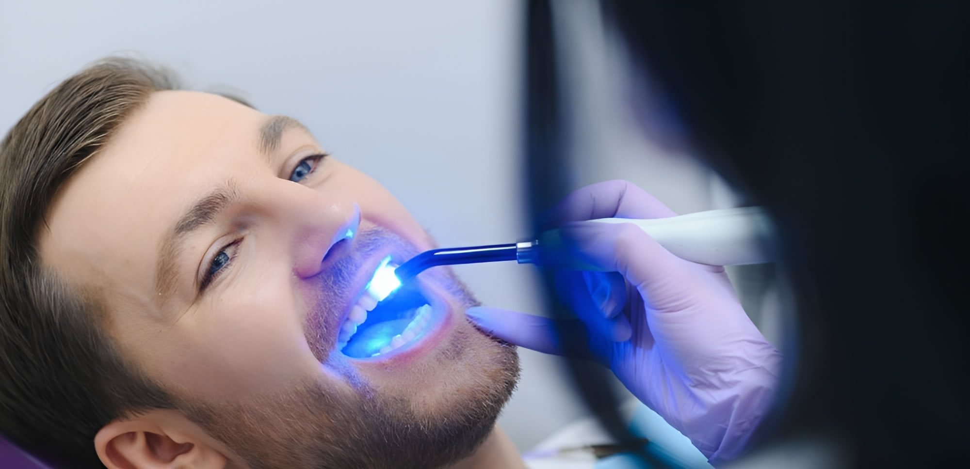 a person using a dental lamp to check the teeth of a man